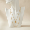 Collar LUNA PERLA doble cadena dorada con dije de perla en torso blanco