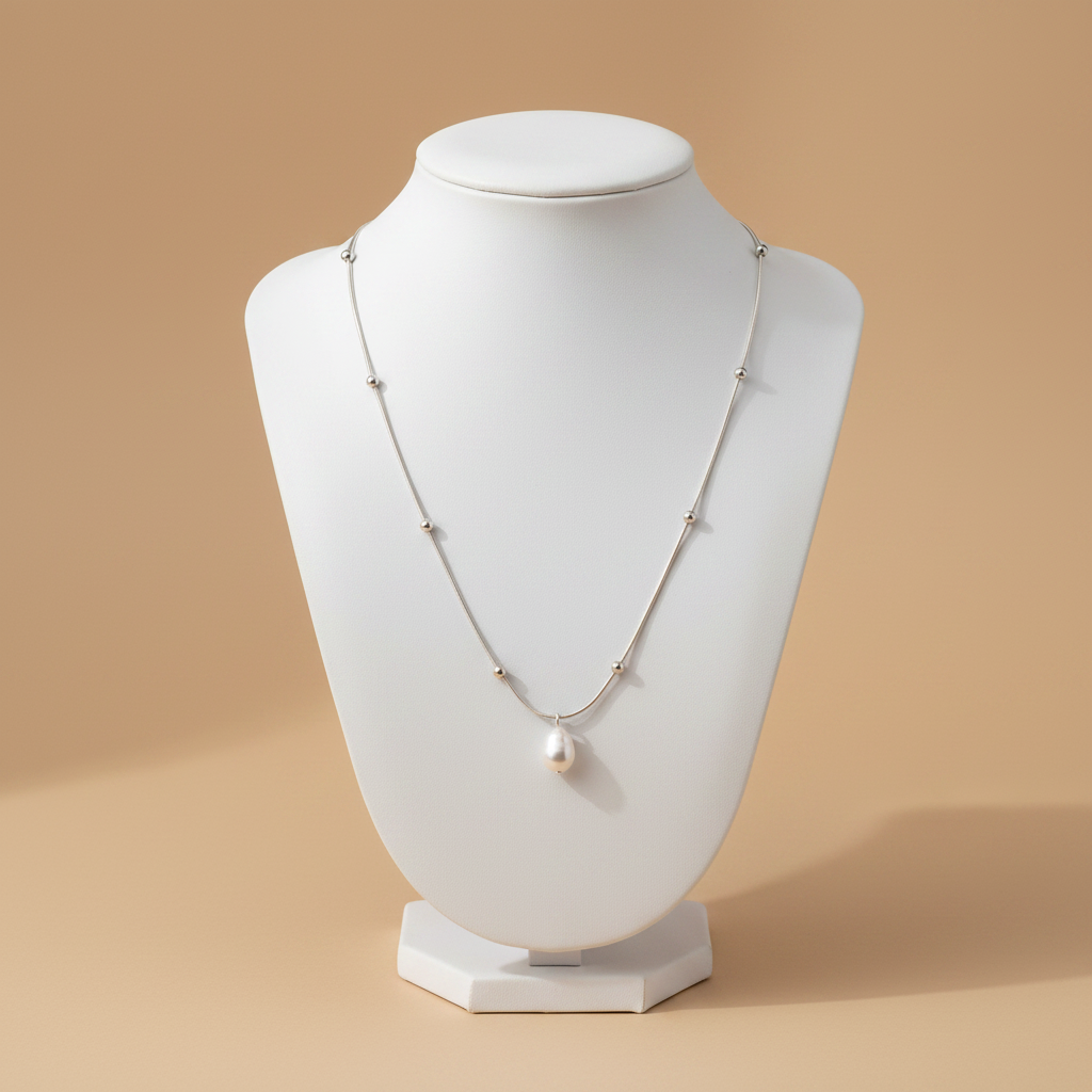 Collar SATÉLITE PERLA cadena plateada con perla barroca colgante en torso beige
